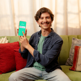 Joven caminando por la calle mientras revisa su nómina en su app móvil.