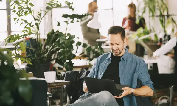 Persona utilizando una computadora portátil para consultar información y gestionar servicios digitales desde un espacio interior cómodo y conectado.