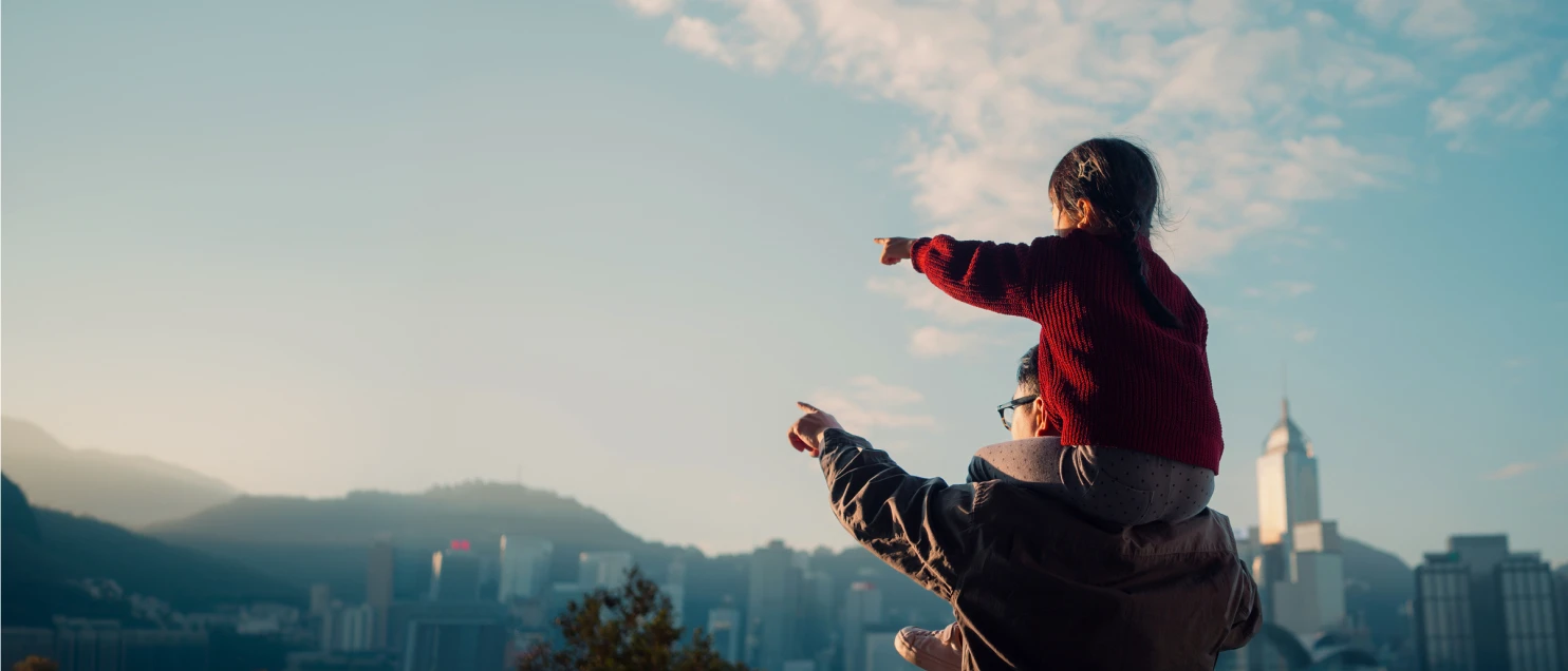 Persona adulta acompañando a un menor mientras observan el horizonte desde un mirador urbano, reflejando protección, bienestar y futuro compartido.